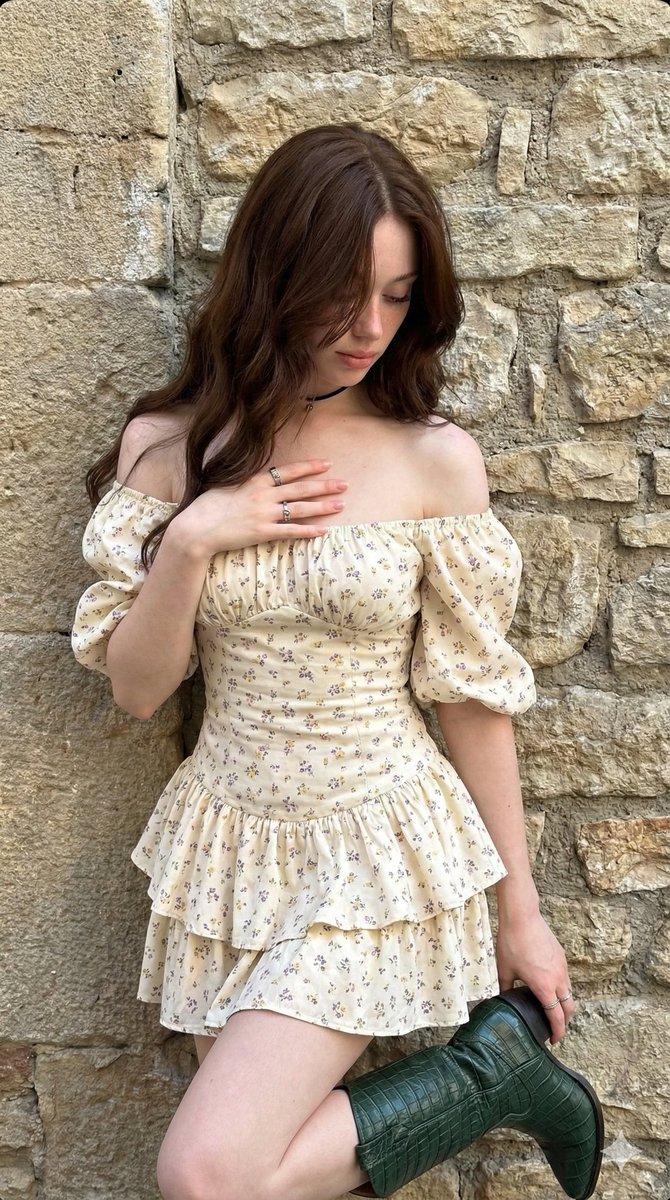 碎花裙少女倚靠石墙手握绿皮靴